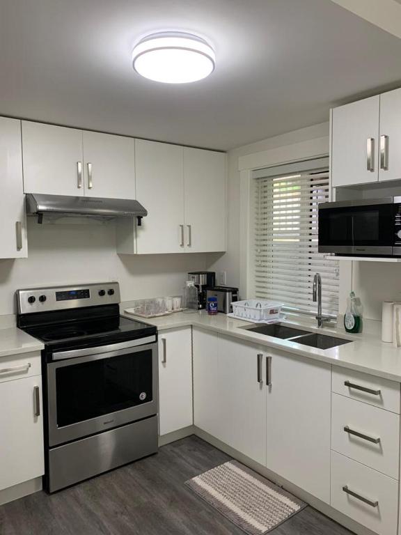 a kitchen with white cabinets and a stove top oven at Gladwin one bedroom in Abbotsford