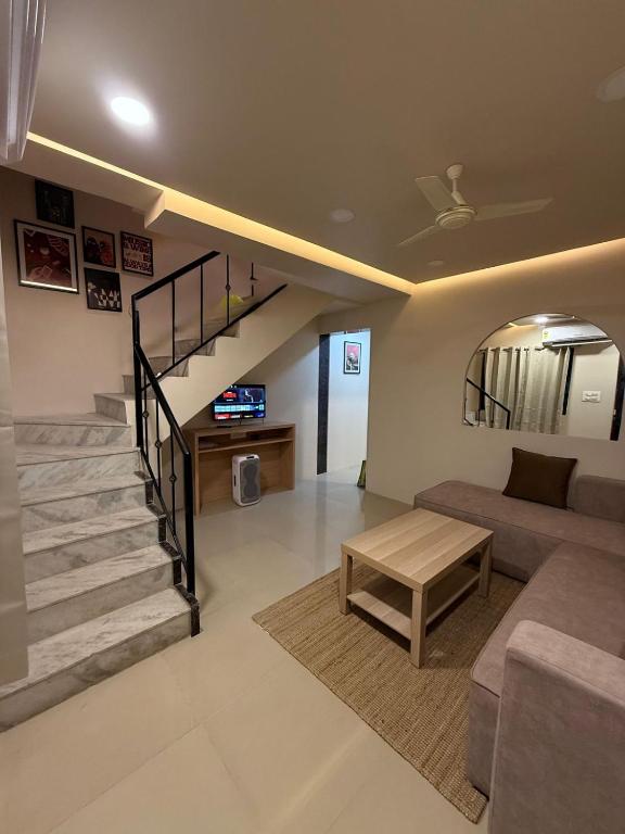 a living room with a staircase and a couch at Jacuzzi Escape Retreat in Kolshet