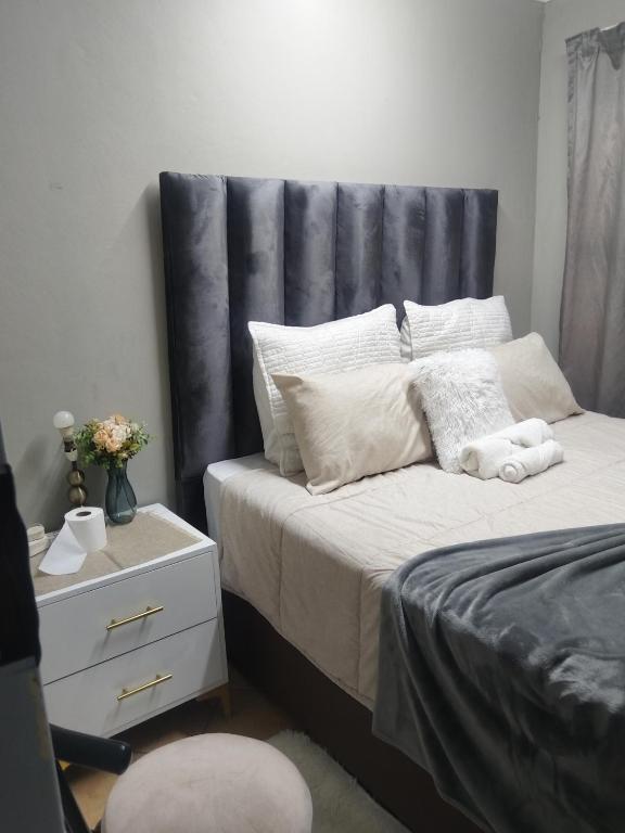 a bedroom with a bed with a gray headboard at Soshanguve Lux Accom Room 02 in Soshanguve