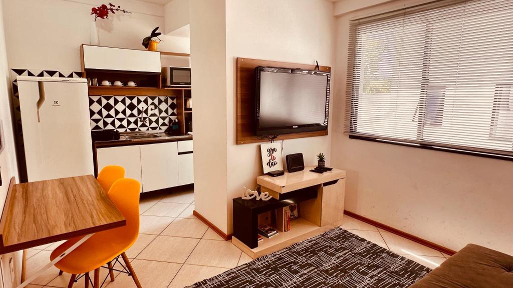 a living room with a television and a table and a kitchen at Aconchego - com Garagem in Santa Maria