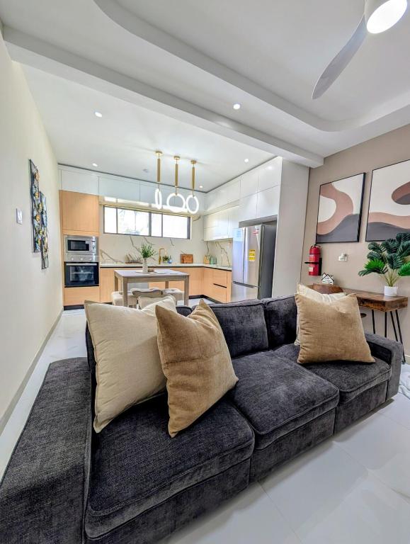 a living room with a black couch and a kitchen at Salt & Breeze Villa in Priory
