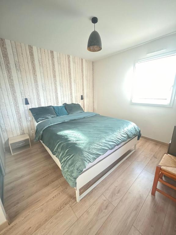 a bedroom with a large bed with a green comforter at Suite parentale chez Mathilde in Basse-Goulaine
