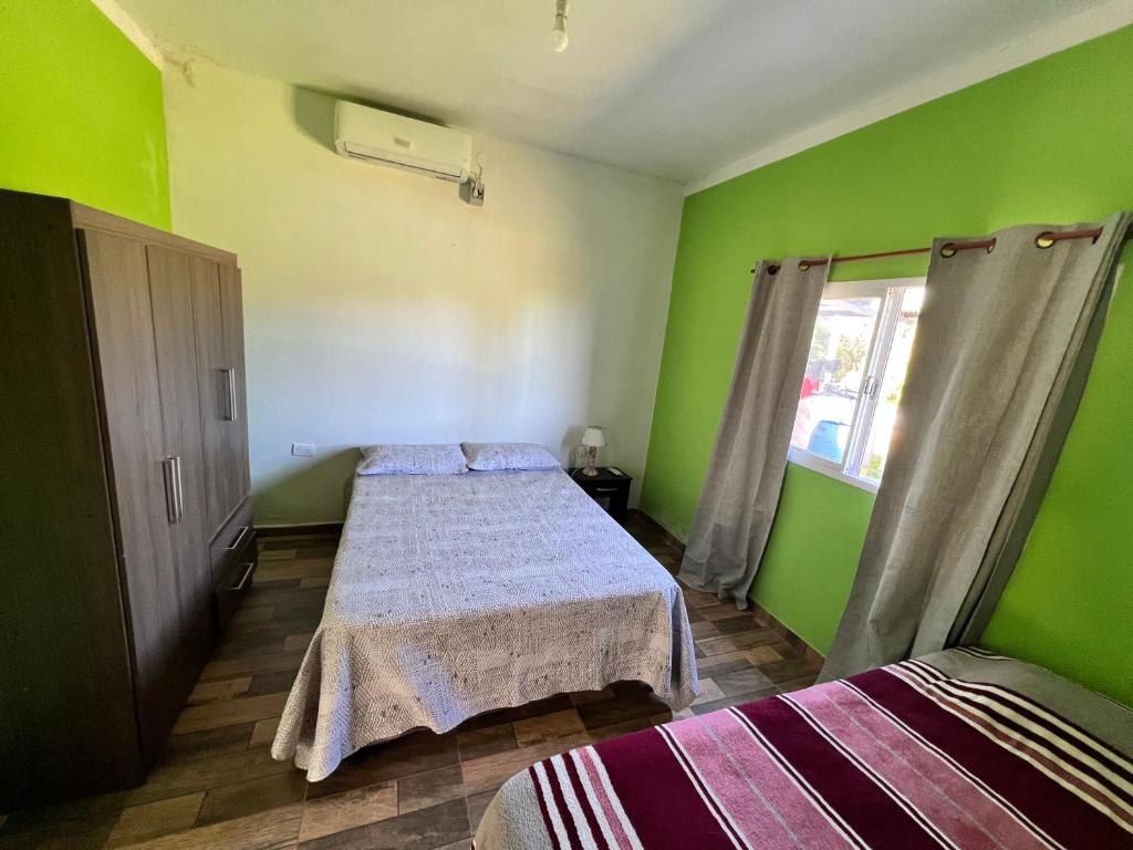 a green room with two beds and a window at Casa en la Puntilla 2 in Belén