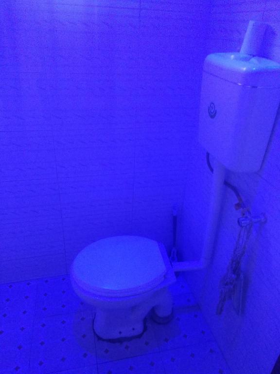 a bathroom with a white toilet in a purple light at Urban-den in Kampala