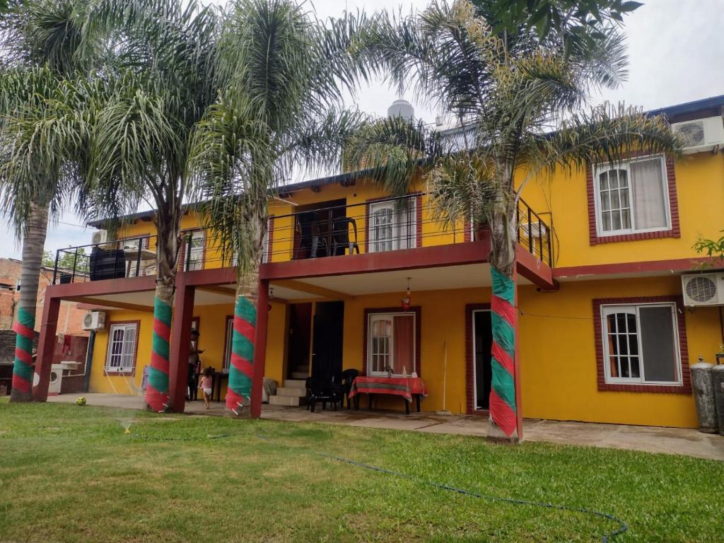 a yellow house with palm trees in front of it at Arena y sol in Colón