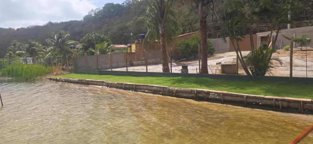 a body of water with a fence and grass at Rancho citrus in Coruripe