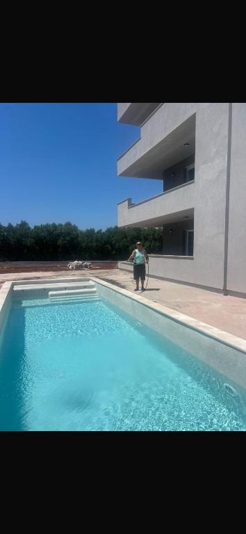 a person standing next to a swimming pool next to a building at Rados Villa Flora in Fažana