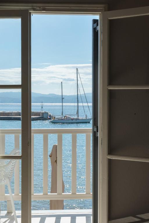 a window with a view of the ocean with a sail boat at Archontiko Seaside Hotel-Beachfront Blue Experience in Platanias