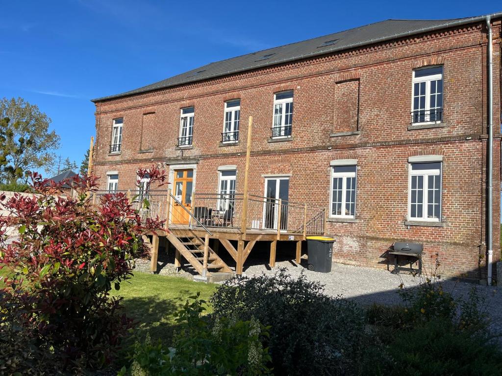 a large brick building with a wooden deck in front of it at La Grisolle de 4 à 14 personnes in Landouzy-la-Cour
