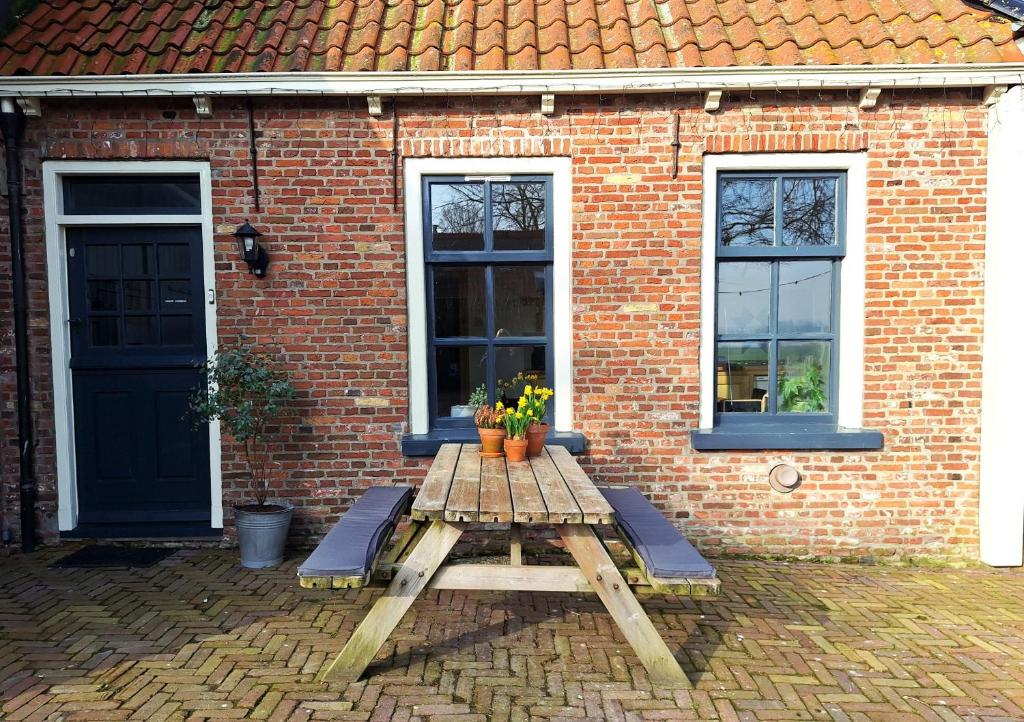 a wooden picnic table in front of a brick building at Logement Alde Leie in Alde Leie