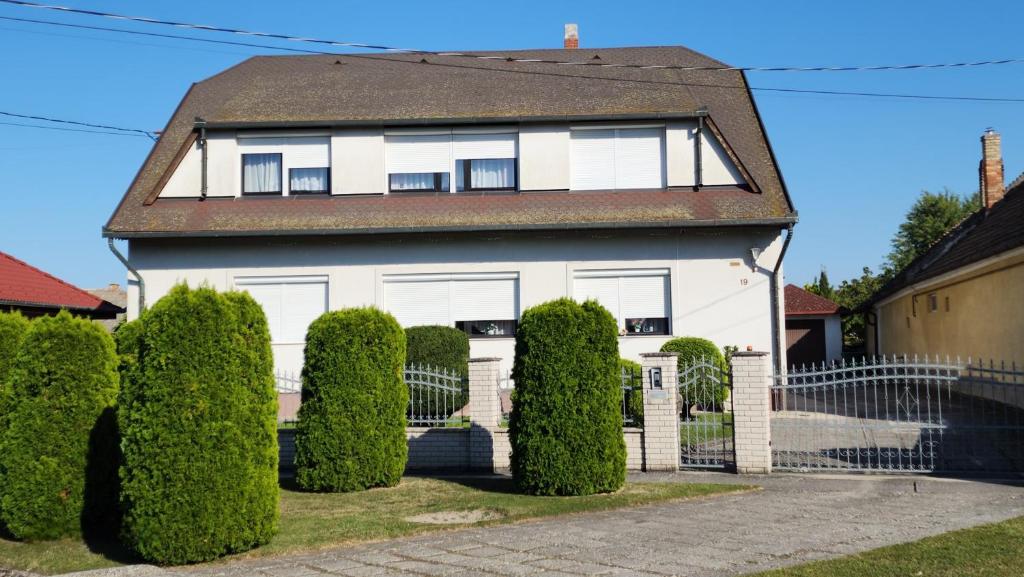 a white house with bushes in front of it at Szigetköz Győrzámoly Apartman in Győrzámoly