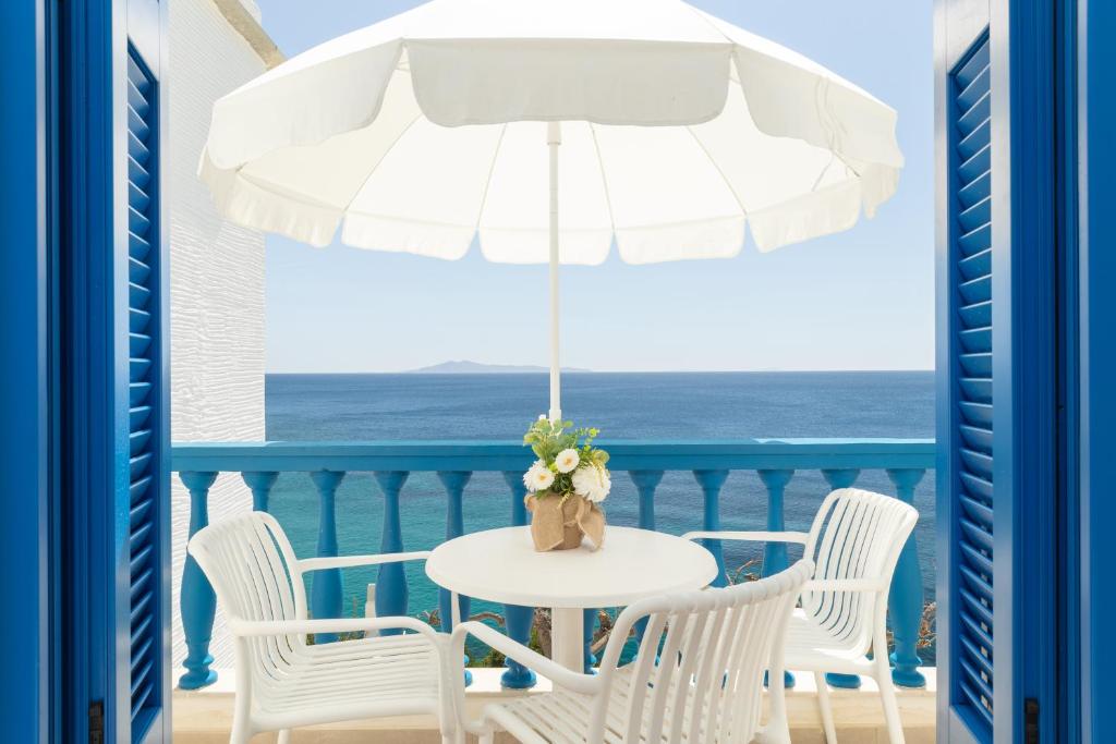 a white table with chairs and an umbrella on a balcony at Apanemo Seaside in Batsi