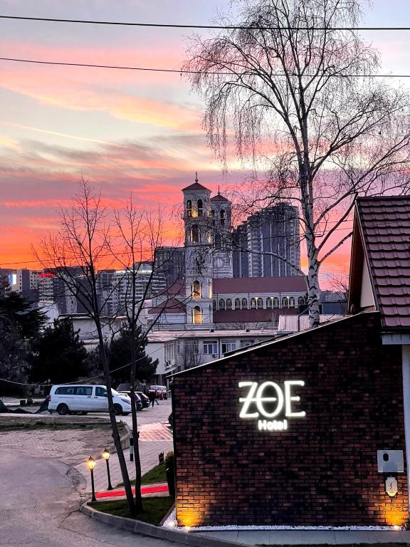 a zoe sign on the side of a building at sunset at Zoe Hotel in Prishtinë