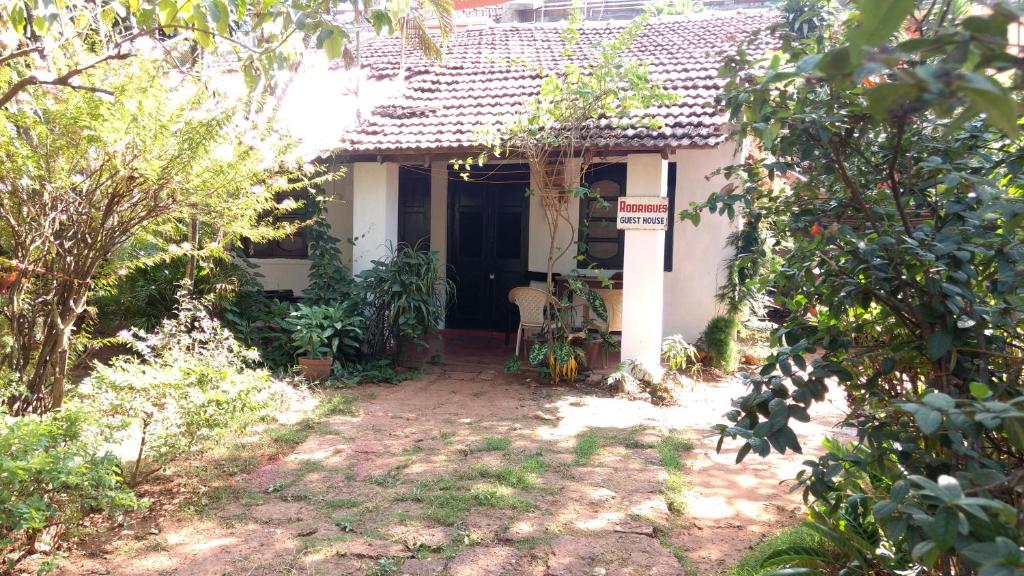 uma pequena casa branca com um sinal em frente em Rodrigues Guest House em Calangute