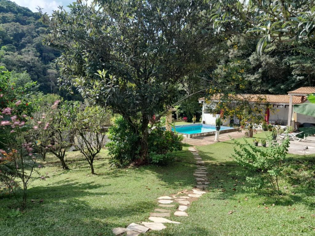 a garden with a tree and a swimming pool at Hostel e Camping Yoshida Naturismus in Ibiúna