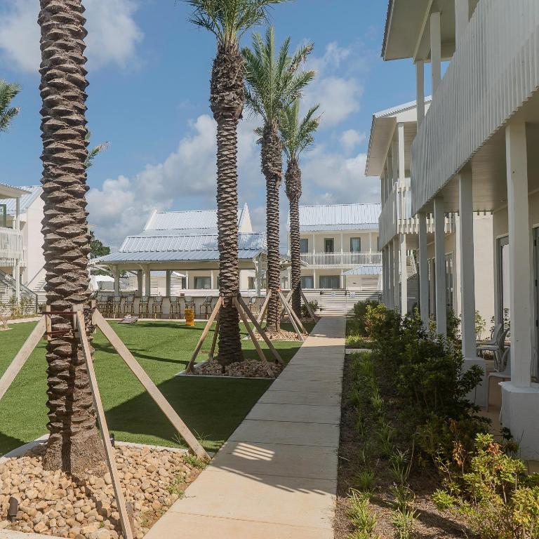 a walkway with palm trees next to a building at The Pass Bungalows in Pass Christian