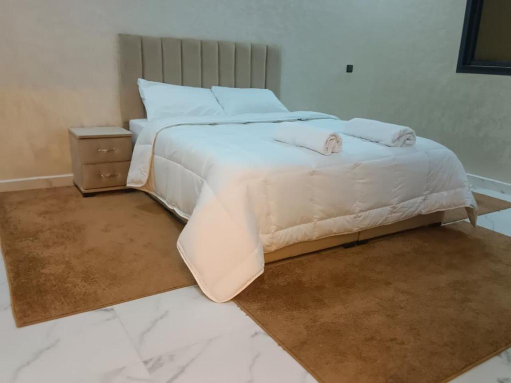 a bedroom with a large white bed and a night stand at شقق تاج الداخلة in Dakhla