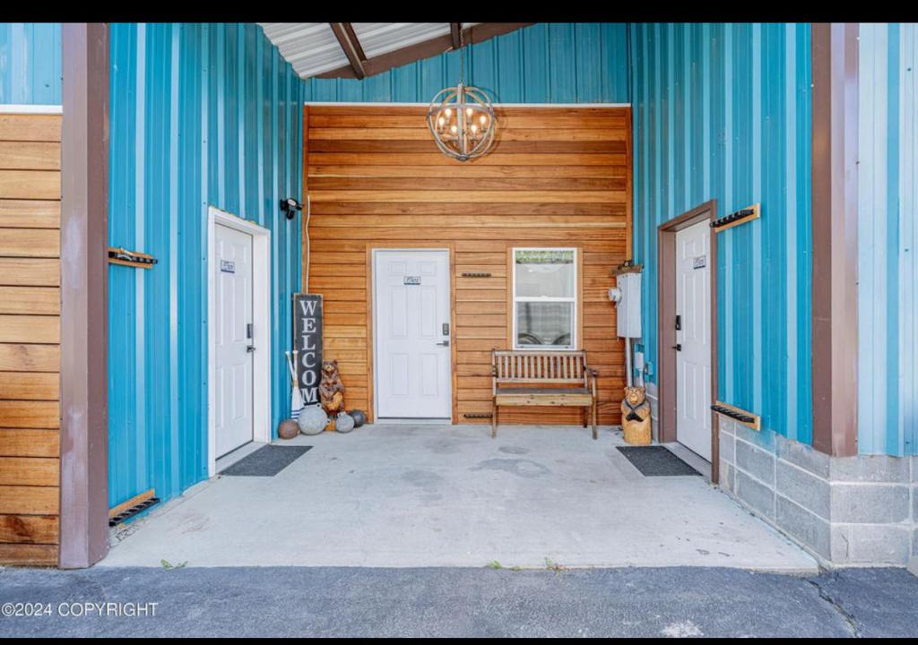a blue building with a bench and two doors at Catch'em AK - Eagles Nest in Soldotna