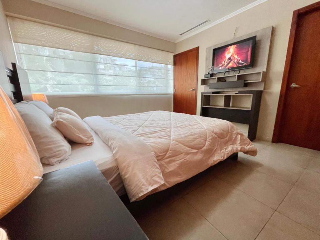 a bedroom with a bed and a tv on a wall at Gallery Suite en Riverfront Puerto Santa Ana in Guayaquil