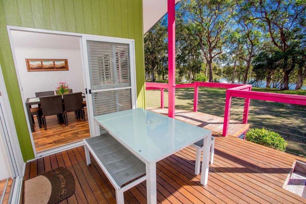 a glass table on a deck with a dining room at Ingenia Holidays South West Rocks in South West Rocks