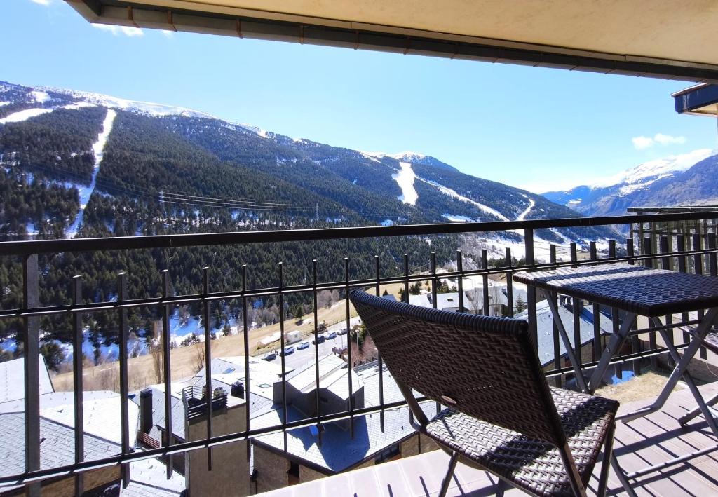a balcony with two chairs and a table and mountains at AC Apartaments Apollo Soldeu in Soldeu