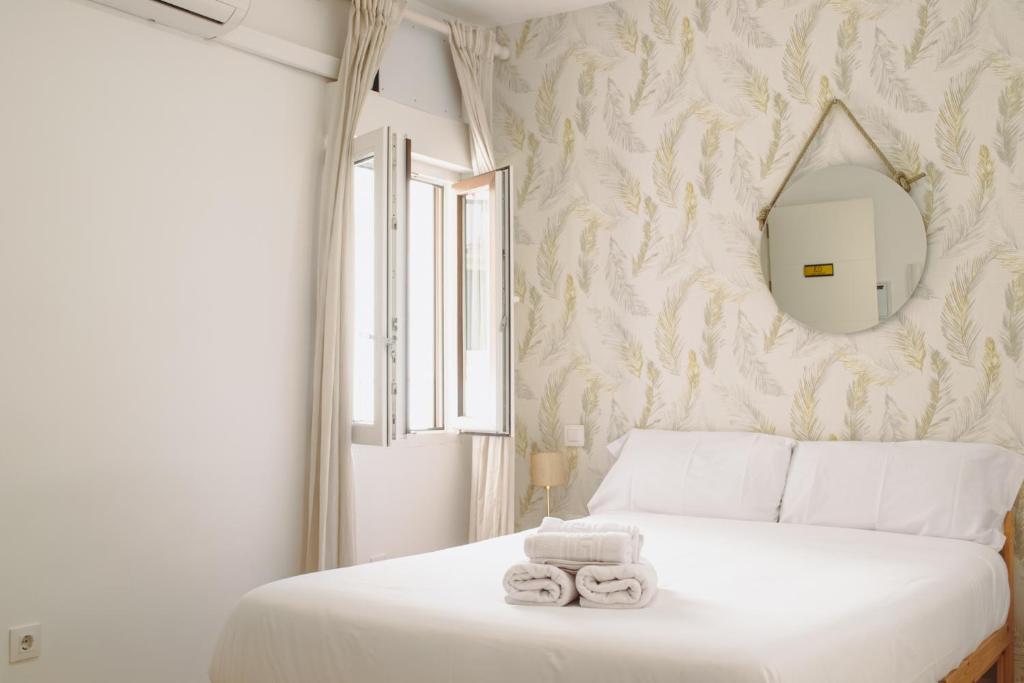 a bedroom with a white bed with towels on it at Apartamentos Sal de Luna in Toledo