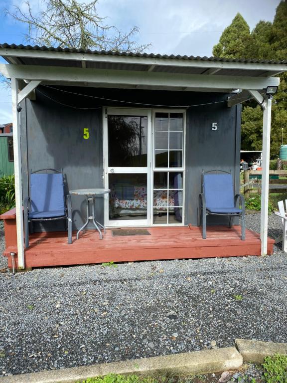 a house with two chairs and a table on a deck at Waitomo Farmstay - Kiwi Cabin 5 in Waitomo Caves
