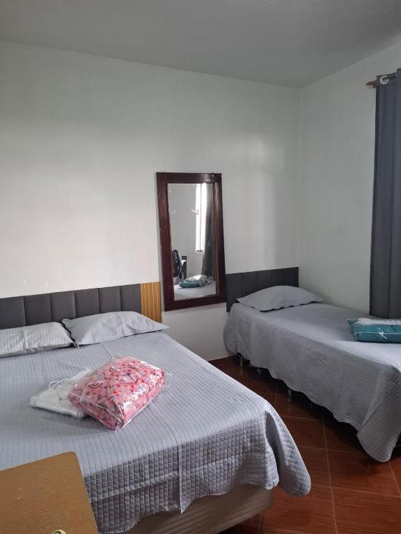 two beds in a room with a mirror and a mirror at Suite confort 02 in Contagem