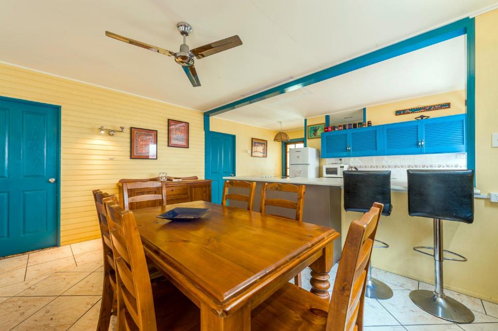 a dining room with a wooden table and a kitchen at Clifton Beach House in Clifton Beach