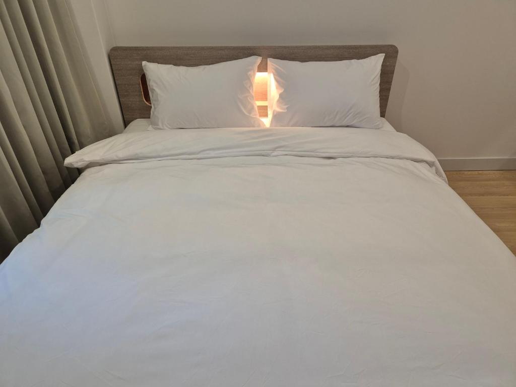 a bed with white sheets and pillows and a lamp at 광장관광호텔 in Pusan