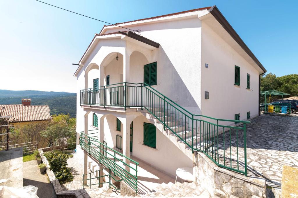 a white building with green shutters and stairs on it at Apartments with parking space Rabac, Labin - 6464 in Rabac