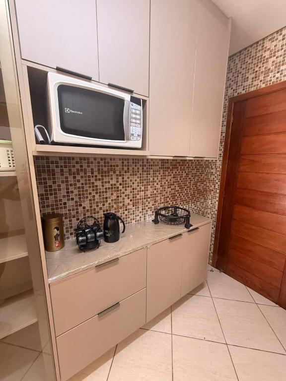 a kitchen with a microwave on top of a counter at Casa de hóspedes in Canoas