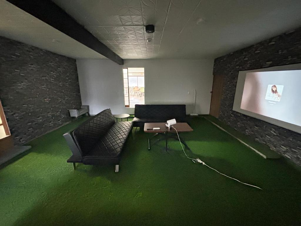 a living room with green carpet and a screen at Seven base Yoshiumi in Imabari