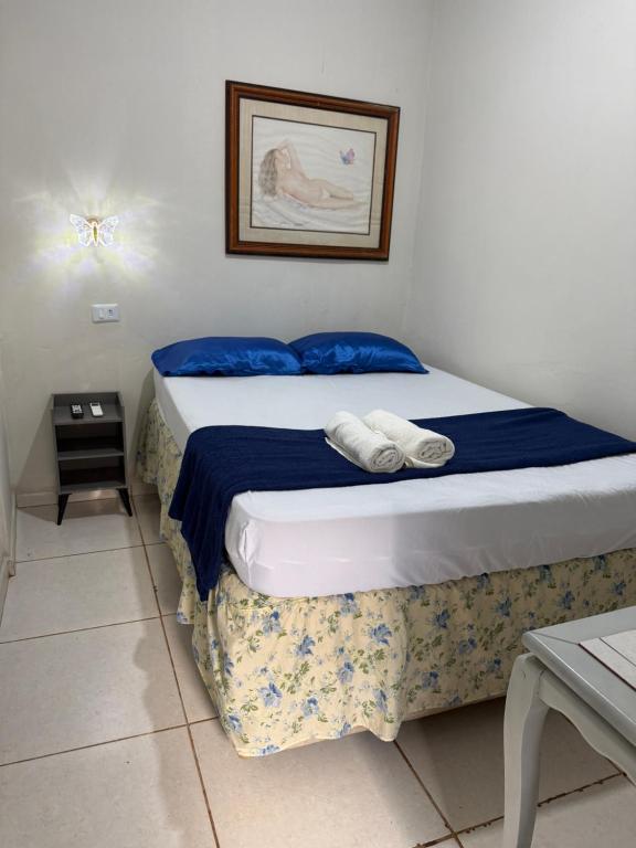 a bedroom with a bed with blue sheets and blue pillows at Pousada brandt Ap 3 in Campo Grande