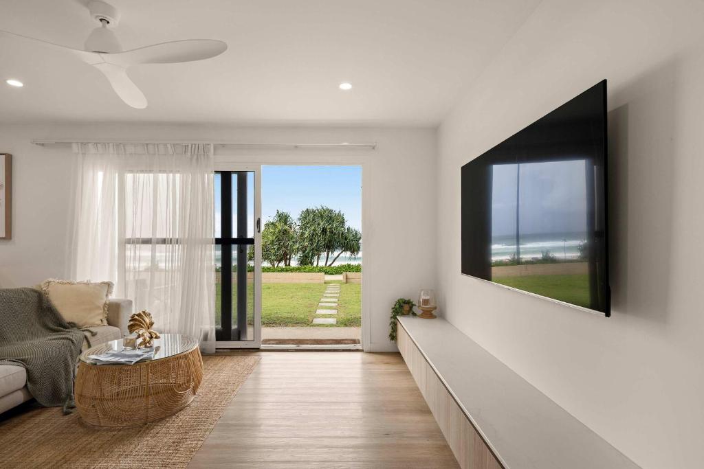 a living room with a couch and a tv on a wall at Little Waves Tugun in Gold Coast