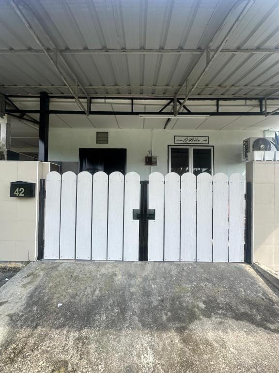 a white fence with a cross in front of a building at Ellhavfiz Homestay in Tapah