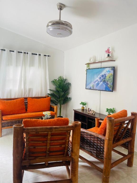 a living room with orange furniture and a tv at Estancia Dulce Hogar, en pedernales in Pedernales