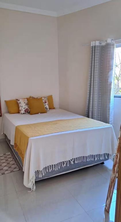 a bed in a white room with a window at Apartamento Aconchegante 3 in Doutor Lund