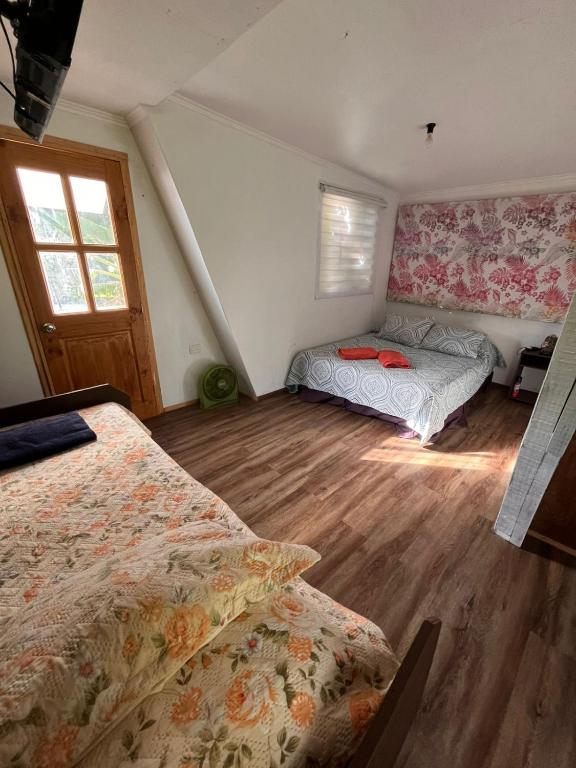a bedroom with two beds and a window at Hospedaje henua roa 2 in Hanga Roa
