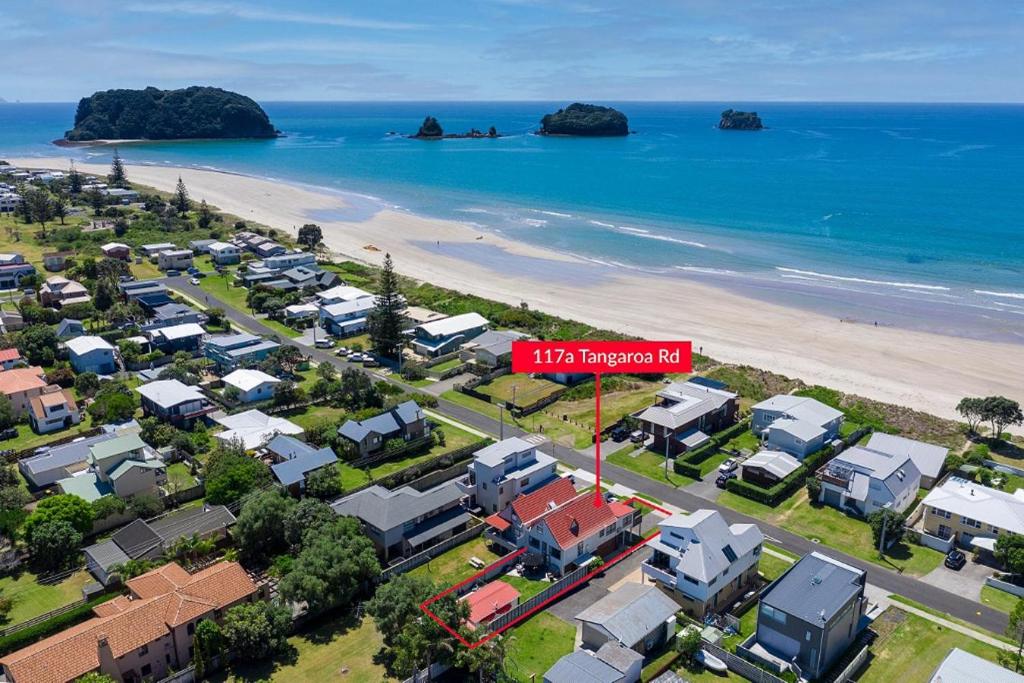 an aerial view of a beach with houses and a red sign at Tangaroa Beachside Bliss - with Private Pool in Whangamata