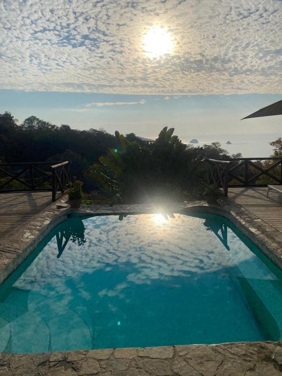 ein großer blauer Swimmingpool mit der Sonne im Hintergrund in der Unterkunft Hotel Sal de Mar in San Agustinillo