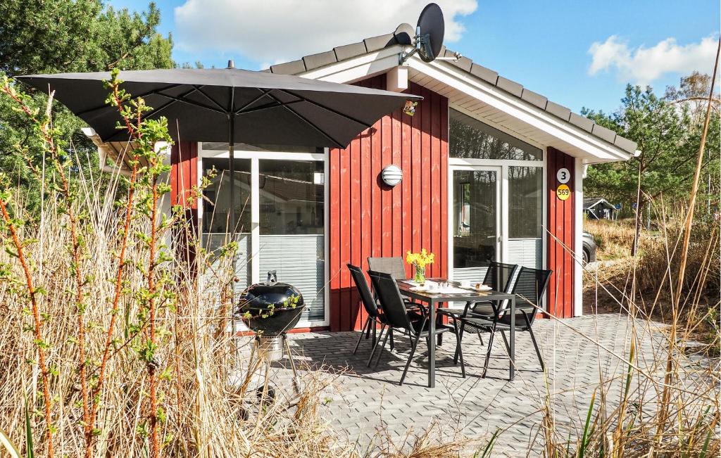 a red shed with a table and chairs and an umbrella at Schatzkiste 3 - Dorf 4 in Travemünde
