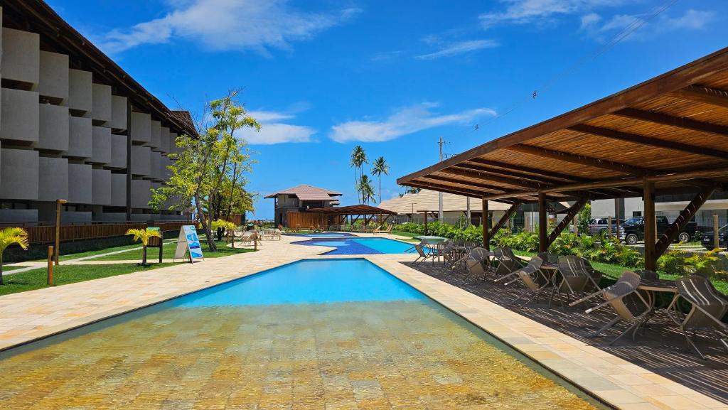a swimming pool with chairs and a building at Studio Beira-Mar na Praia dos Carneiros in Tamandaré
