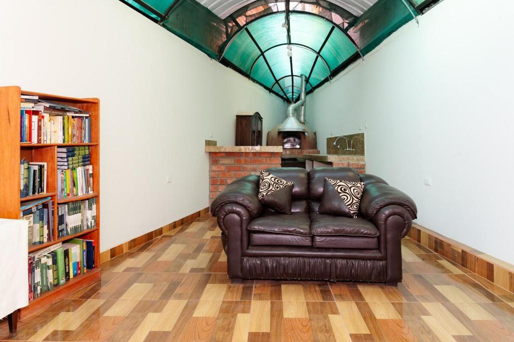 a leather couch in a living room with a book shelf at Comfortable apartment in Urubamba in Urubamba