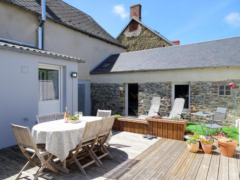 a patio with a table and chairs on a deck at Stone House in Bricqueville near Sandy Beach in Bricqueville-sur-Mer