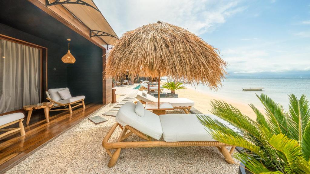 a room with chairs and an umbrella and the beach at Sea Sun Beach Villa in Nusa Lembongan