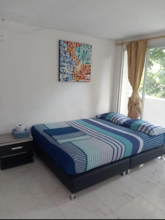 a bed in a bedroom with a picture on the wall at Hostal Sur Tosc in Cali