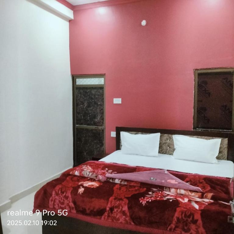 a bedroom with a bed with a red wall at Shree krishna guest House near Ram mandir in Ayodhya