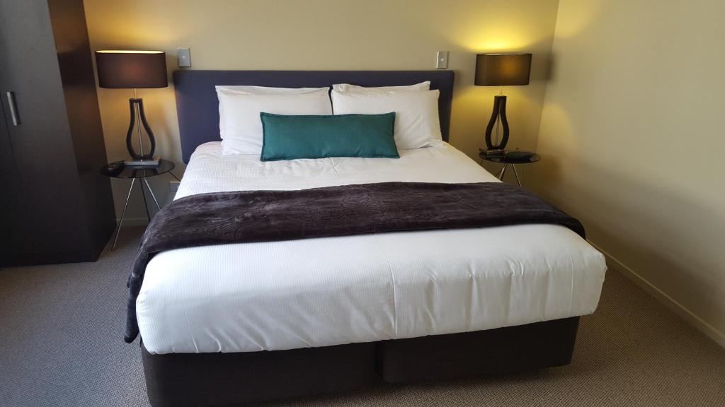 a bedroom with a large bed with a blue pillow at Sails on the Lake in Taupo