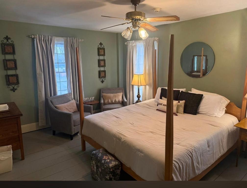 a bedroom with a bed and a fan and a chair at Historic Rider's Hostelry in Painesville